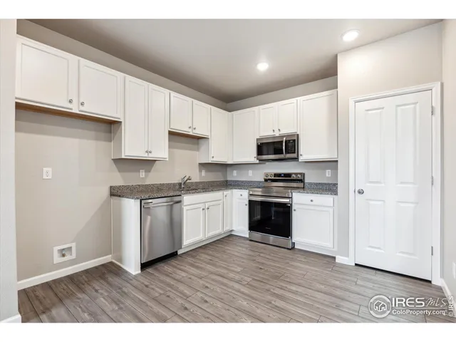 a kitchen with granite countertop a refrigerator and a stove top oven