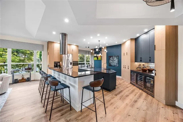 a kitchen with stainless steel appliances kitchen island granite countertop a stove a refrigerator a sink a dining table and chairs with wooden floor