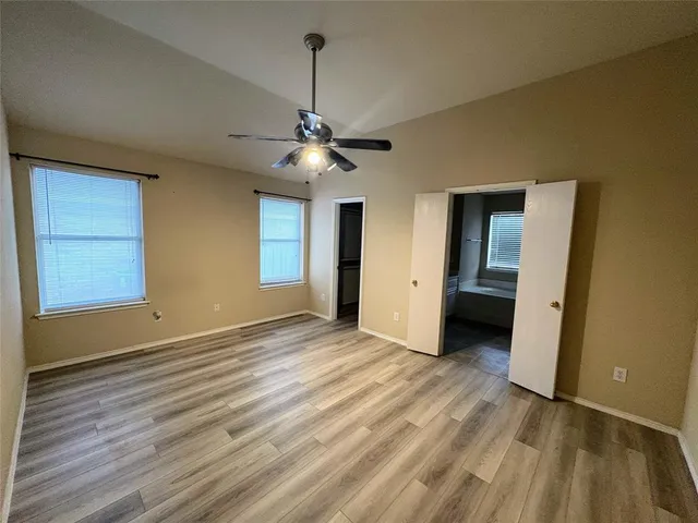 a view of an empty room with window and wooden floor