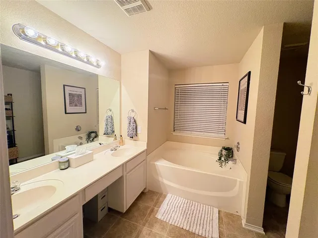 a bathroom with a tub a sink and a large mirror