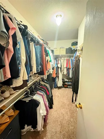 a view of walk in closet with clothes and shoes