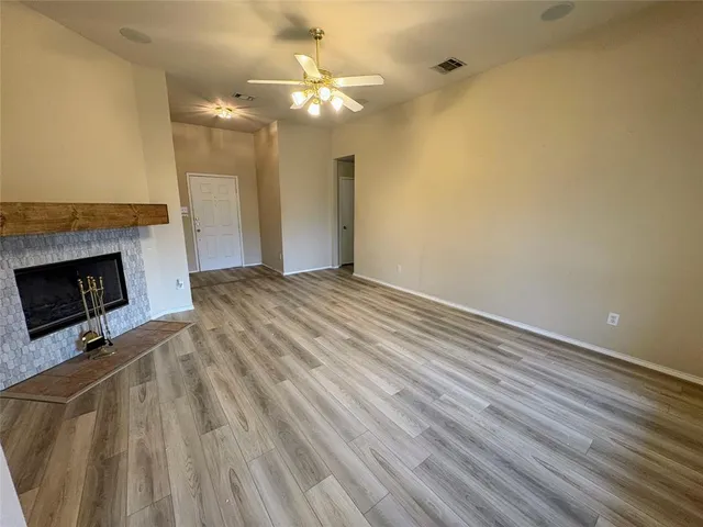 en empty room with wooden floor fireplace and chandelier