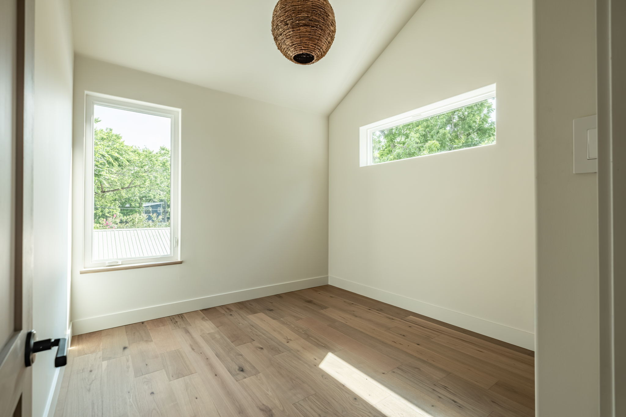 4713 Bolm Road Austin, TX 78702 - Photo 34 of 40 Vaulted ceiling room featuring light wood-finish flooring, a contemporary woven pendant light fixture, and two distinct windows providing natural illumination