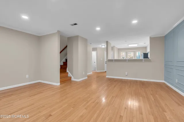 a view of a room with wooden floor and a kitchen