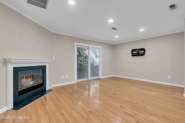 a view of an empty room with wooden floor fireplace and a window
