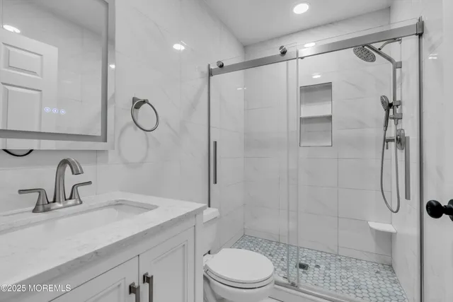 a bathroom with a shower sink vanity mirror and toilet