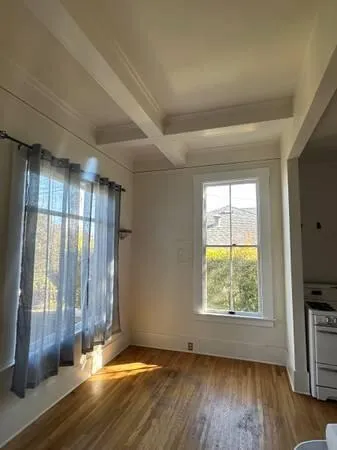 a view of an empty room with a window and wooden floor