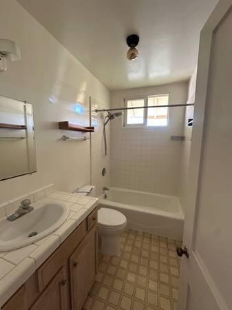 1629 Garden Street, Unit 1 Santa Barbara, CA 93101 - Photo 7 of 12 a bathroom with a granite countertop sink a toilet a mirror and shower