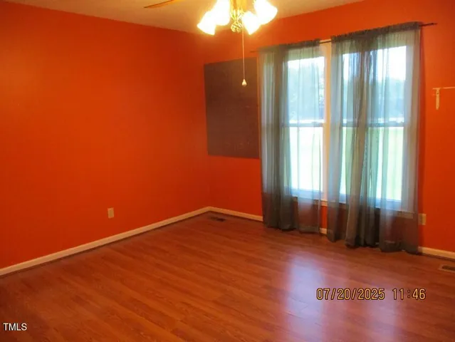 a view of an empty room with wooden floor and a ceiling fan