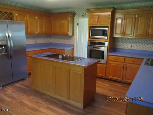 a kitchen with stainless steel appliances granite countertop a refrigerator a stove and a sink