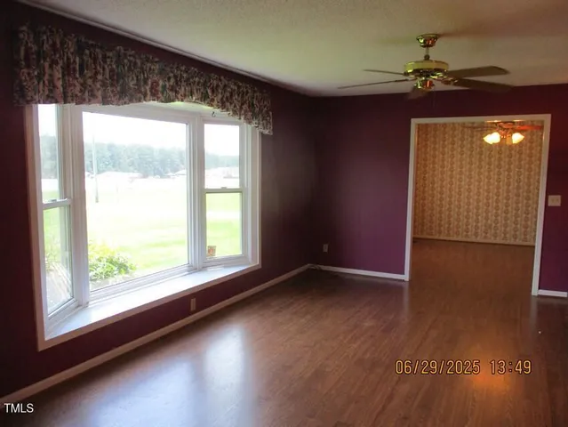 a view of an empty room with a window and wooden floor
