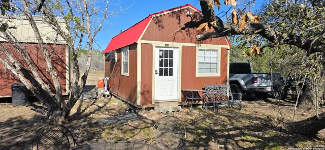 a view of a house with a large tree and sitting area