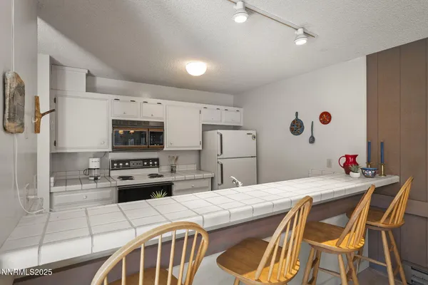 a kitchen with stainless steel appliances kitchen island a table chairs and a refrigerator