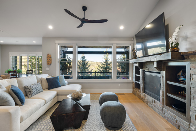 1737 East Viewside Circle Hideout, UT 84036 - Photo 2 of 35 Spacious living area featuring expansive windows, a modern ceiling fan, wood-finish flooring, and a stone-clad fireplace with built-in shelving