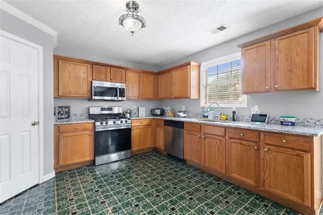 a kitchen with stainless steel appliances granite countertop a stove a sink and a microwave