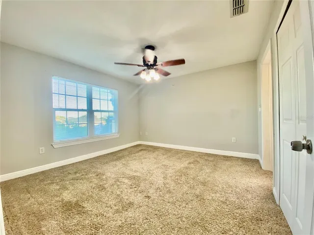an empty room with a window and ceiling fan