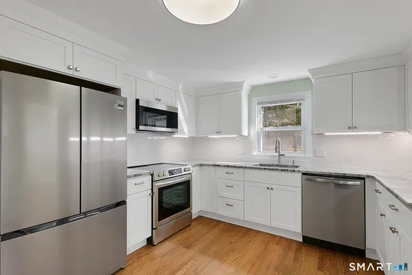 a kitchen with granite countertop white cabinets and white appliances