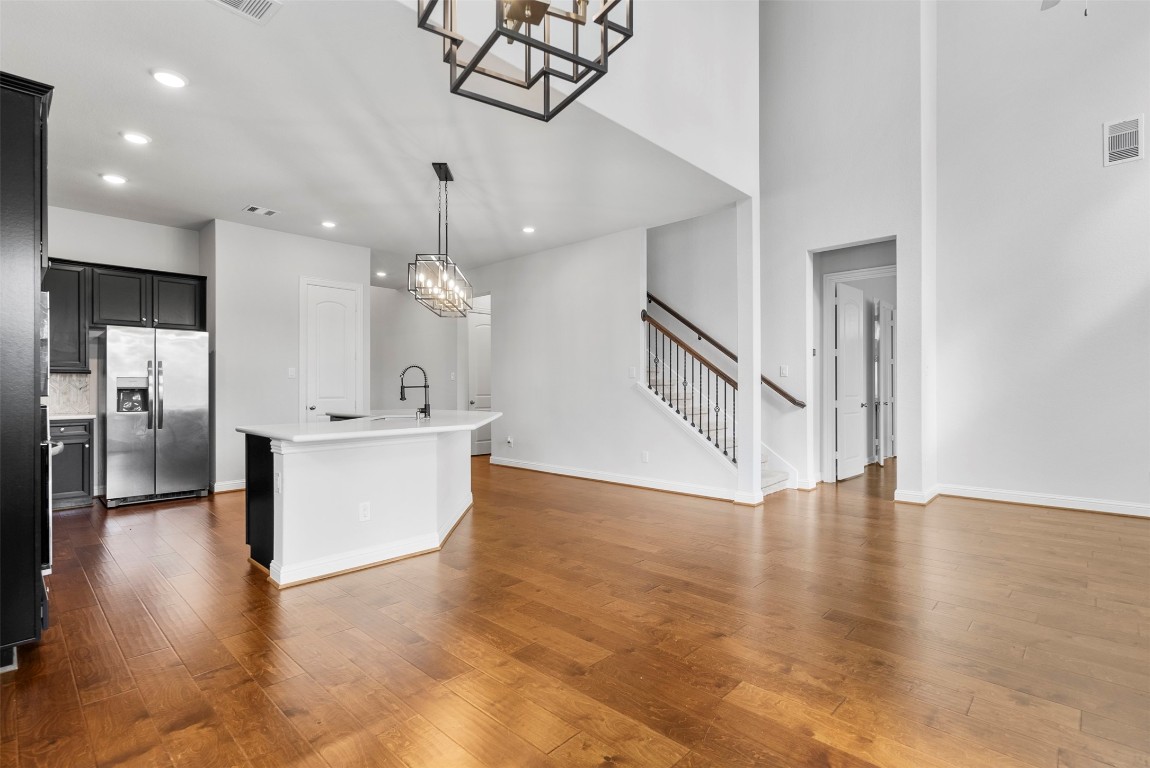 148 Gray Pne Grove Conroe, TX 77318 - Photo 16 of 46 a view of an empty room and kitchen with sink wooden floor and a chandelier