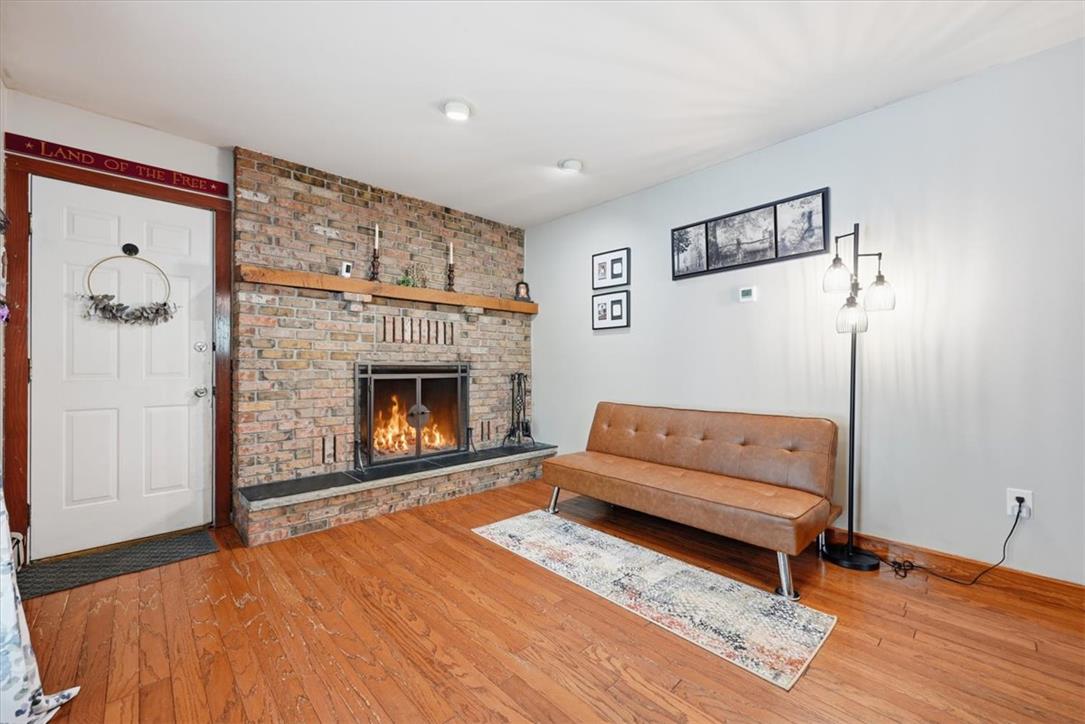 7722 Sechler Road New Tripoli, PA 18066 - Photo 9 of 58 Rich hardwood flooring anchors the room alongside a classic floor-to-ceiling brick fireplace with wood mantel.