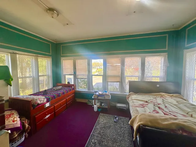 a bedroom with a bed and large windows