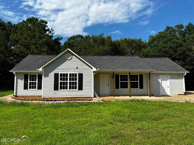 a front view of a house with a yard and trees
