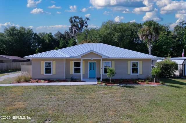 a front view of house with yard and trees in the background