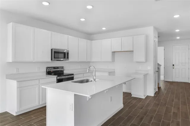 a kitchen with a sink a stove a refrigerator and white cabinets