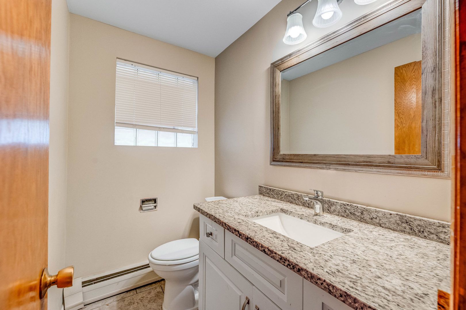 5626 West 64th Street, Unit 2 Chicago, IL 60638 - Photo 4 of 11 a bathroom with a granite countertop toilet sink and mirror