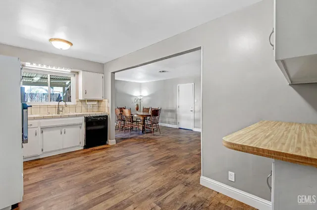 a kitchen with stainless steel appliances granite countertop a stove top oven a sink dishwasher a dining table and chairs with wooden floor