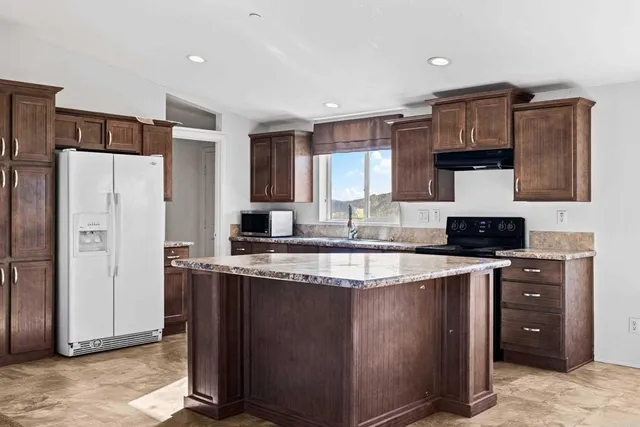 a kitchen with stainless steel appliances granite countertop a stove a refrigerator and a sink