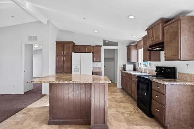 a kitchen with stainless steel appliances granite countertop a stove top oven a sink a counter space and cabinets