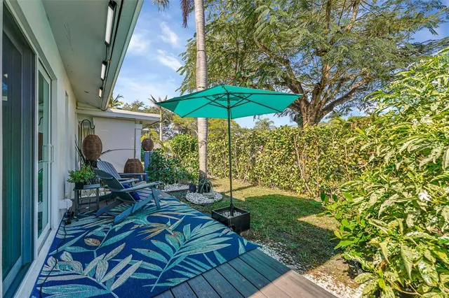 a view of a house with backyard sitting area and blue umbrellas