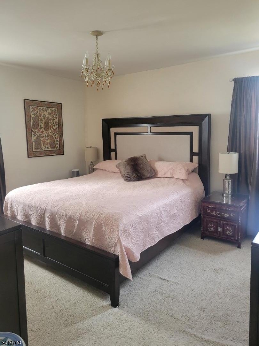 117 Tillotson Road Fanwood, NJ 07023 - Photo 22 of 30 a bedroom with a bed lamp and a chandelier