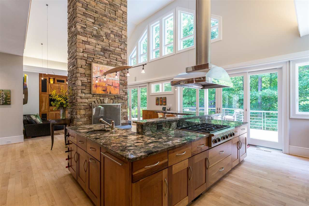1117 Baslow Brook Court Raleigh, NC 27614 - Photo 13 of 30 A large multi-level U-shaped island with Brazilian Verde Marinace granite counter includes a lower wing w/stainless-steel vegetable prep sink, a long section with a gas stove and work surfaces backing up to a higher serving counter. Exceptionally Designed Kitchen