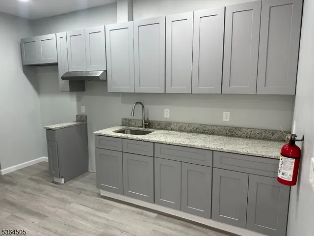 a kitchen with stainless steel appliances granite countertop a sink a refrigerator and a white cabinets