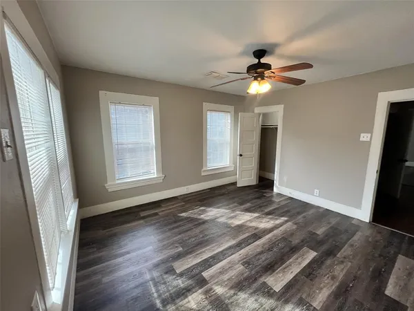 a view of an empty room with window and wooden floor