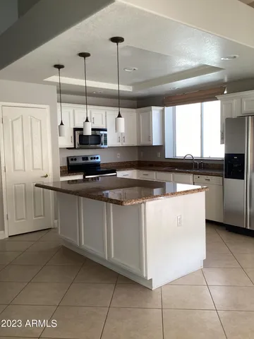 a kitchen with kitchen island granite countertop a sink a counter top space cabinets and stainless steel appliances