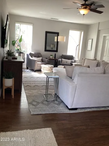 a living room with couches and a flat screen tv with kitchen view