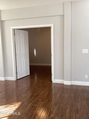 a view of an empty room with wooden floor and closet