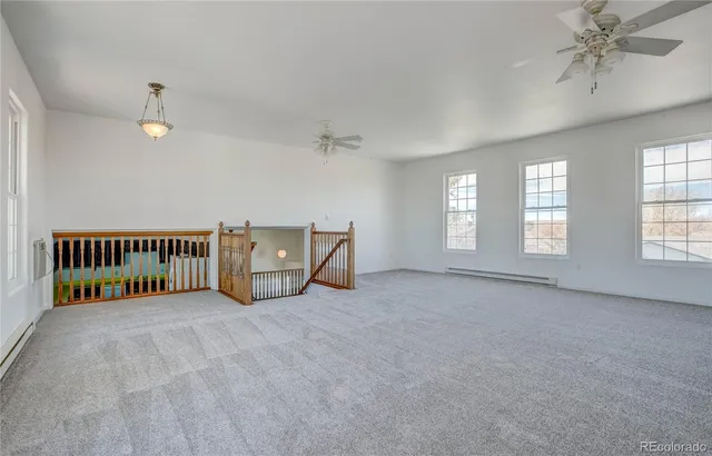 an empty room with windows and ceiling fan