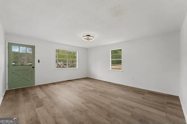 an empty room with wooden floor and windows