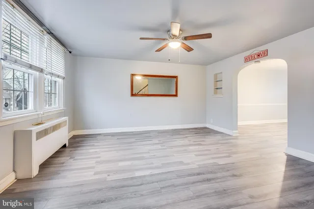 a view of an empty room with a window and wooden floor