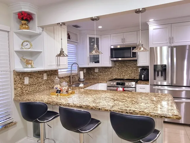 a kitchen with stainless steel appliances granite countertop a stove refrigerator a sink dishwasher and microwave