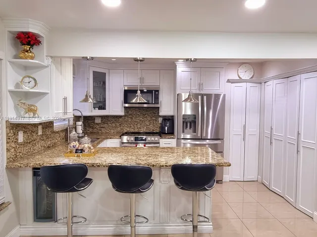 a kitchen with stainless steel appliances granite countertop a refrigerator and a stove top oven