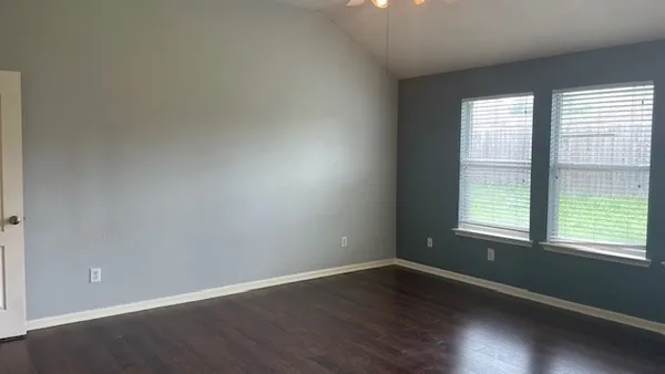 a view of an empty room with wooden floor and a window
