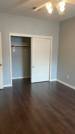 a view of an empty room with wooden floor and closet