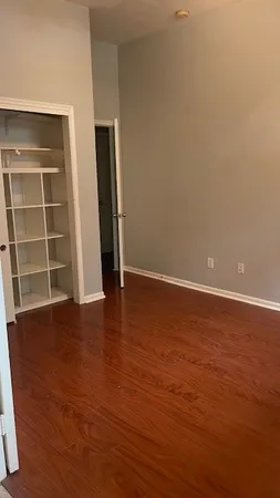 a view of an empty room with wooden floor and windows