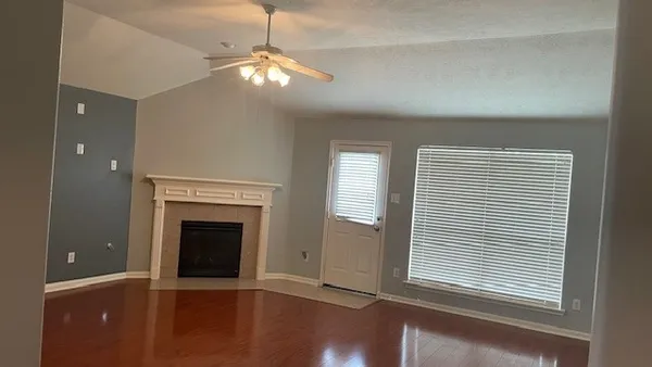 an empty room with windows and fireplace