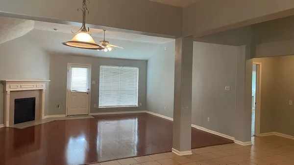 a view of an empty room with wooden floor fireplace and a window