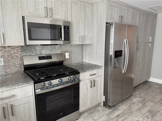 a kitchen with stainless steel appliances white cabinets a stove top oven